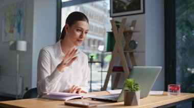 İnternetteki toplantıda konuşan Freelancer, çalışma masasında defter sayfalarını çeviriyor. Modern ofisteki gülümseyen iş kadını görüntüsü. İnternet konferansında danışmanlık yapan zarif bir bayan notları okuyor..