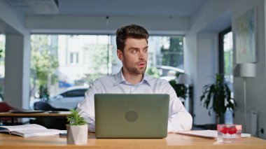 Şirket çalışanı dizüstü bilgisayarla iş yerini kapatmaya odaklanmış. Şirket işyerinde çalışan ciddi bir iş adamı. Tıraşsız girişimci açık alanda istatistik belgeleri okuyor