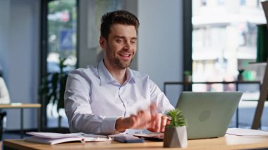 Gülümseyen bir çalışan bilgisayarın kapağını kapatıyor ve modern ofis açık alanda başarılı bir projeden memnun. Mutlu iş adamı çevrimiçi işi bitirir. Yönetici beklenen başarılı bilgisayarı kapatıyor