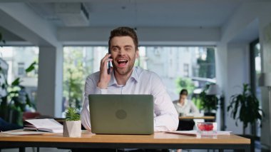 Gülümseyen danışman cep telefonuyla konuşuyor. Laptop iş yerinde çalışıyor. Yakın plan. Ofiste cep telefonuyla yapılan açık alanda danışmanlık yapan olumlu bir yönetici. Başarılı iş adamı akıllı telefonları kapalı alanda pazarlıyor..