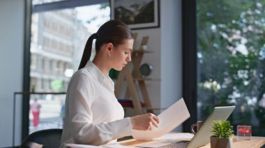 Profesyonel yönetici, şirketin açık alandaki yakın çekimlerinde kendini başarılı hissetmekle meşgul. Gülümseyen iş kadını dizüstü bilgisayar başında mali raporları okuyor. Mutlu bayan kağıtlardaki kar verilerinin keyfini çıkarın.