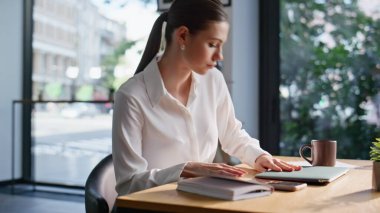 Güzel müdür, sabah yakın planda elinde kahve fincanıyla ofis masasında oturuyor. Kendine güvenen iş kadını şirket açık alanındaki iş gününe başlıyor. Zarif iş kadını çevrimiçi çalışmaya hazırlanıyor