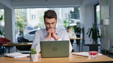 Düşünceli girişimci, modern çalışma alanlarını kapatarak iş dünyasına çözümler bulmaya çalışıyor. Gergin adam yönetici ofis dizüstü bilgisayarına bakıyor. Bilgisayarda çalışan düşünceli iş adamı çözme görevi.