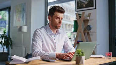 Dizüstü bilgisayarda, organize ofis işyerinde oturan, somurtkan yönetici tipi e-posta. Bilgisayar başında çalışan ciddi bir iş adamı. Çalışma alanında çevrimiçi proje geliştiren yakışıklı yönetici.