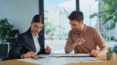 Finans müdürü, ofis masasında hesap makinesini gösteren bir müşteri ile pazarlık yapıyor. Gülümseyen kadın danışman iş adamına yatırım tavsiyesi veriyor. İki iş ortağı birlikte belgeleri tartışıyor..