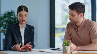 Banka müdürü, ofis masasında oturan müşteriye hesaplamaları gösteriyor. Profesyonel iş kadını ortağıyla finans projesini hesaplıyor. Sigorta danışmanı.
