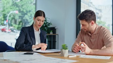 Sigortacı, ofis masasında hesaplamalar yaparak müşteri ile konuşuyor. Profesyonel danışman iş adamına sigorta sözleşmesini açıklıyor. Ortaklar iş toplantısında anlaşmayı tartıştılar.