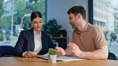 İş danışmanı, anlaşma detaylarını ofis masasındaki erkek yatırımcıya açıklıyor. Dost canlısı kadın İK müdürü erkek müdürle iş sözleşmesini sonlandırıyor. Profesyonel işadamı anlaşma imzalıyor..