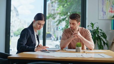 İş ortakları bütçeyi planlarken projeyi yakın planda tutuyorlar. Kadın mali danışman, ofisteki erkek müşteriye hesap yapıyor. Banka müdürü iş adamına kredi hesaplıyor..