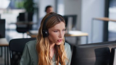 Satış temsilcisi kulaklıkla konuşuyor. Ofis açık, yakın plan. Profesyonel kadın yardımcı operatör müşteriye uzaktan yardım ediyor. Hizmet sunan genç iş kadını.