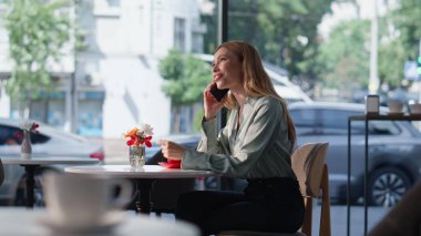 Modern restoran masasında tek başına konuşan neşeli sarışın. Garson kafeteryaya kahve getirirken gülümseyen güzel bir kadın arıyor. Mola yerinde akıllı telefondan konuşan mutlu bayan.