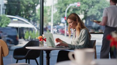 İş kadını kafeteryada dizüstü bilgisayar yazıp sıcak kahvenin tadını çıkarıyor. Rahat kadın serbest çalışan, kafeteryada çalışan bir proje yaratıyor. Restoranda internette profesyonel girişimci sörfü.