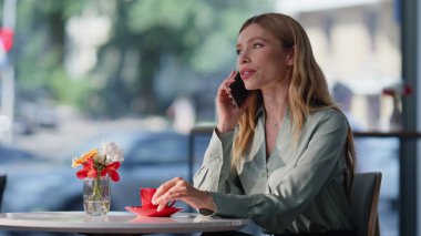 Samimi kafeterya masasında oturan kendine güvenen bir bayan konuşuyor. Kahve molasında cep telefonuyla konuşan güzel bir iş kadını. Zarif sarışın lokantada dinleniyor..