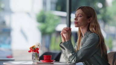 Kahve parasını ödeyen kadın kafe müşterisi modern iç çekimde oturuyor. Arkadaş canlısı bir garson, Ulaşılmaz ödeme için akıllı telefonu kullanarak POS terminalini sarışın müşteriye getiriyor. NFC teknoloji kavramı.