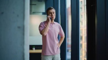 Gülümseyen adam ofis müdürü modern kabinede akıllı telefon ile konuşuyor. Yakışıklı bir iş danışmanı, müşterilerle cep telefonu aygıtı kullanarak konuşuyor. Mutlu adam uzaktan telefon görüşmesi yapıyor.