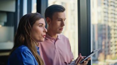 Kapanış şirketi yöneticileri, gökdelenlerin arka planında pencerenin yanında duran işleri konuşuyorlar. Tabletteki inşaat projesini analiz eden iki mimar. İçeride strateji tartışan birkaç meslektaşıma ilham verdim. 