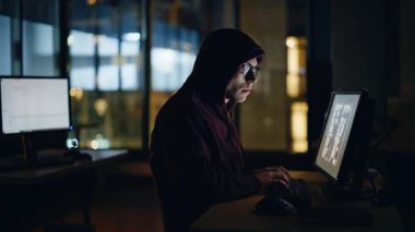 Hacker gece yüksek teknoloji odasında veri bilgisayarı klavyesi yazıyor. Odaklanmış casus programcı, güvenlik sistemi sunucularını hackliyor. Sadece karanlık veritabanı iş yerindeki şirket sunucularını.