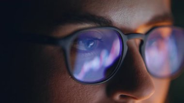 Gözlük, karanlık yerde yansıyan diyagramlara bakıyor. Konsantre tüccarın yüzü, akşam ofisindeki borsa finans verilerini analiz eden bilgisayarla çalışıyor. İnternet 'te sörf yapan kadın uzmanı. 