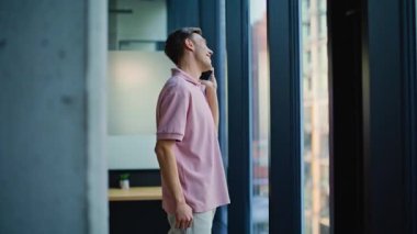 Light Home 'a yakın çekimde pozitif serbest çalışan akıllı telefon çağrısı. Gülümseyen mutlu yönetici cep telefonundan konuşuyor. Rahatlamış, kaygısız bir adam mutfakta durmuş cep telefonuyla sohbet ediyor. Çalışan sohbetin tadını çıkarıyor 