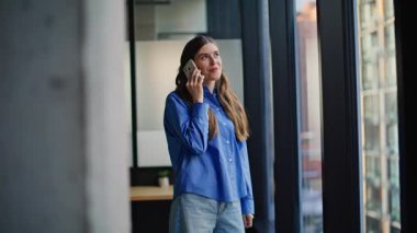 Modern apartmanda cep telefonunu arayan serbest çalışan biri var. Akıllı telefon kullanan çekici, gülümseyen bir kadın. Mutlu bayan yönetici telefonda konuşuyor. Evde yalnız başına kaygısız hissediyorum.