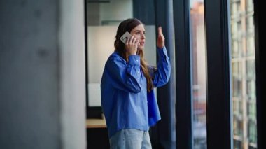 Memnun olmayan kadın CEO 'nun akıllı telefonu araması ofis panoramik penceresinden el hareketi yapması. Sinirli iş kadını cep telefonuyla kontrat hatasından yakınıyor. Sinirli bayan sadece telefonla sorunu tartışıyor. 