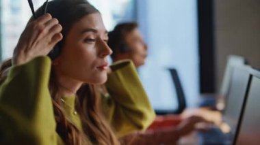 Operatör elleri ofiste kulaklık takıyor. Çağrı merkezinde çalışan, kulaklık takan ciddi bir ajan. Kadın temsilci modern ortamda uzaktan yardım sağlıyor