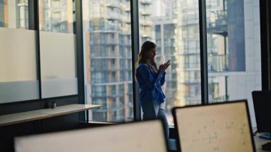 Lüks bir ofiste cep telefonuna mesaj atan mutlu bir iş kadını. Panoramik pencere dairesinde akıllı telefon ekranına bakıp gülümseyen zarif bir bayan. Sadece telefon mesajını okuyan tatmin olmuş bir iş kadını.