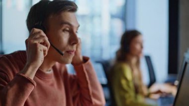 Ajan Hand monitörden kulaklığı alıyor. Çağrı merkezinde çalışan profesyonel teknik asistan bilgisayar görüntüsü. Genç yardım hattı yöneticileri, danışman müşteriyle sohbet ediyorlar. Müşteri desteği işi