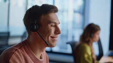 Çağrı merkezinde yakın çekim teknik asistanı konuşuyor. Odaklanmış operatör, müşteri dinleme isteği çevrimiçi çözüldü. Gülümseyen destek ajanı kulaklıkla müşterilere danışmanlık yapıyor. Yardım masası kariyer konsepti