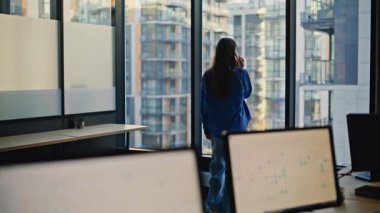 Ciddi bir kadın patronun ofis penceresinde cep telefonunu araması. Zarif kıyafetli esmer iş kadını iş için akıllı telefon kullanıyor. Yöneticinin elinde cep telefonu olması olumlu bir konuşma. 