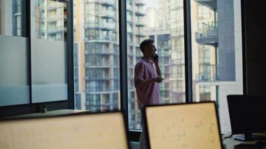 Pozitif yönetici ofis penceresinde cep telefonunu arıyor. İş arasında arkadaşça sohbet etmek için akıllı telefonu kullanarak gündelik kıyafet giyerken mutlu başlangıç. Cep telefonu tutan adam olumlu konuşuyor. 