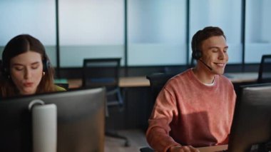 Servis masası çalışanları müşterilerine danışmanlık yapıyor. Açık alanda oturuyorlar. Profesyonel ekip yardım hattında çalışan bilgisayarları arıyor. Müşteri desteği sağlayan kulaklıkta çağrı merkezi personeli