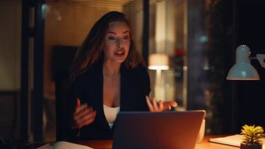 Neşeli iş kadını videosu akşam şirketinin ofisinde çalışıyor. Profesyonel mutlu kadın internette el kol hareketi yapıyor. Gülümseyen strateji uzmanı uzaktan kumandalı konferansta