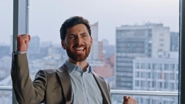 Neşeli şirket lideri duygusal olarak yakın plan görüntüsünde tezahürat yapıyor. Muzaffer menajer heyecanını göstermek için kollarını kaldırıyor. Zengin, kendine güvenen yönetmen cam duvarlar dolabında finansal ödülün keyfini çıkarıyor.