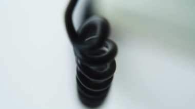 Telefon kablosu yumuşak spiral şeklinde gerilerek retro alıcıyı kapatıyor. Makro görüntü sarmalanmış telefon ses kablosu içeride. İletişim için klasik cihazın siyah spiral teli. Eski tarihi model.