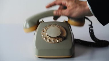 Beyaz arkaplandaki döner telefonları yakın plan çekimde kaldır. Tanınmayan bir adam hafif bir iç mekanda alıcının telefonunu alıyor. İletişim cihazı için klasik minimal dekor. Tarihi model.