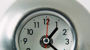 Macro manzaralı mekanik saat, sessiz odada gümüş yüzeyde ellerini hareket ettiriyor. Dairesel nesne, sessiz zamanı odaklanmış ritimle ölçüyor. Saati, dakikaları ve saniyeleri gösteren zarif metal cihaz..