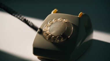 Akşam lambasından ahizeyi almak için el ile telefon numarası çeviriliyor. Tanımlanamayan bir adam içerideki eski sabit telefonu kullanarak arama yapıyor. Eski dairesel numaralandırılmış parmak döndürme mekanizması.