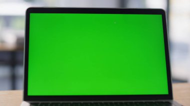 Çalışma masasında yakın plan modern yeşil ekran dizüstü bilgisayar görüntüsü. Çağdaş çalışma alanında dijital görevler için krom anahtar bilgisayar hazır. Şık ofis ortamında verimlilik için profesyonel teknolojiler