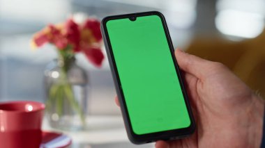 Yeşil ekran akıllı telefonu dinleyen bir adam kahve dükkanı masasının kapanışında online uygulama açıyor. Bilinmeyen adam cep telefonundaki mesajları tarıyor. Patron içeride krom anahtarlı cep telefonunu tutuyor.