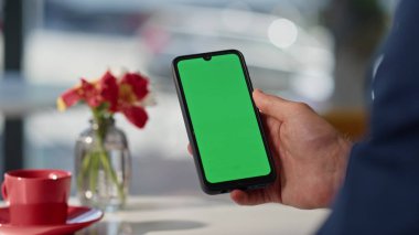 Kafe masasında yeşil ekran cep telefonu mesajı okuyan patron elini tutuyor. Bilinmeyen iş adamı bankacılık uygulaması yeşil ekran cep telefonuna bakıyor. Resmi takım elbiseli adam restoranda video içeriği izliyor.