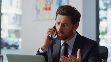 Sinirli CEO panoramik iş yerinde akıllı telefonu tartışıyor. Çılgın sakallı adam cep telefonu diye bağırıyor ve iç mekanda iş sorunlarını tartışıyor. Stresli yönetmen el hareketleriyle iş yerinde oturuyor. 