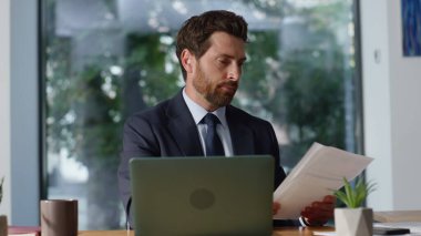 Ofis işyerinde çalışan sakallı girişimci evraklarını yakından inceleyin. Neşeli iş adamı sözleşmeyi okurken tatmin oluyor. Yakışıklı yönetici iş planları pazarlama stratejisi üzerinde kafa yoruyor 