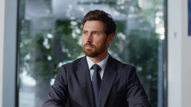 Başarılı yönetici özel kabineyi kapatıyor. Düşünceli iş adamı kameraya özgüvenle bakıyor. Ofisin içinde takım elbiseyle poz veren sakallı profesyonel yönetici. İş hayatı konsepti 