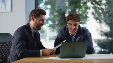 Panoramik çalışma alanı kapanışında iş arkadaşları laptopunu arıyor. Pozitif iş adamları şirket kabinesinde online konferansta işleri tartışırken el ele tutuşuyorlar. Sanal buluşmada konuşan iki iş arkadaşı.