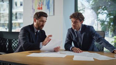 Stresli ortaklar şirket işyerinde kağıtları tartışıyorlar. Profesyonel borsacı yatırımcıya danışmanlık yapıyor. Mali belgelerde hata olduğunu gösteriyor. İş arkadaşları istişare sırasında gergin hissediyorlar