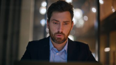 Akşam ofisinde çalışan ciddi bir girişimci dizüstü bilgisayarın yakın çekimini yapıyor. Sakallı iş adamı portresi. Tapınağa masaj yapıyor. Zor konuları düşünüyor. Gergin yönetici iş planlama stratejisi.