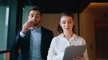 Başarılı meslektaşlar yakın plan anlaşmasını tartışıyor. Gülümseyen işadamı kahve içiyor ve güzel bir iş arkadaşıyla konuşuyor. Dost canlısı ortaklar salonda kağıtları inceliyor..