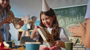 Doğumgünü kızı kutlama hediyeleri veriyor. Sınıf arkadaşlarıyla birlikte, dekore edilmiş sınıf kapanışında. Mutlu liseli kız arkadaşlarına hediyeler alıyor. Gülümseyen kadın öğretmen akıllı telefondan kutlama yapıyor..