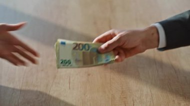 Şirket çalışanları, modern masa içlerindeki para demetlerini transfer ediyorlar. Kadın muhasebeci sessizce iş adamına para notu veriyor. Finansal danışman profesyonel ortamda fon kabul ediyor